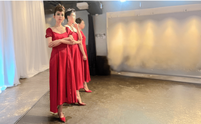 赤いドレスを着てポーズを取る講師