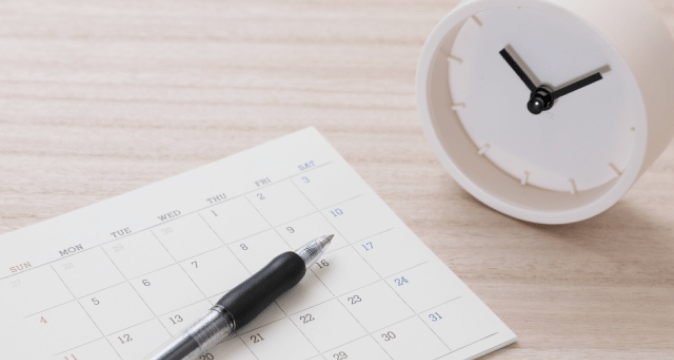 机に置かれた時計とスケジュール帳